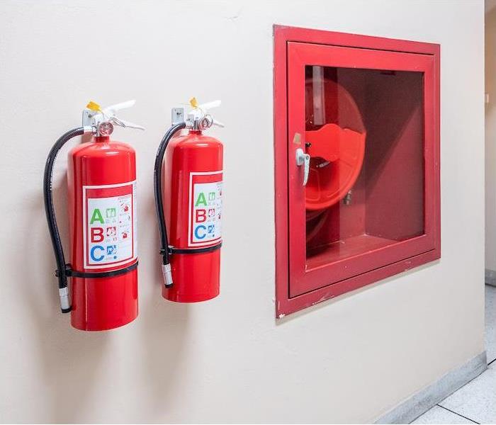 two fire extinguishers hanging on a tan interior wall